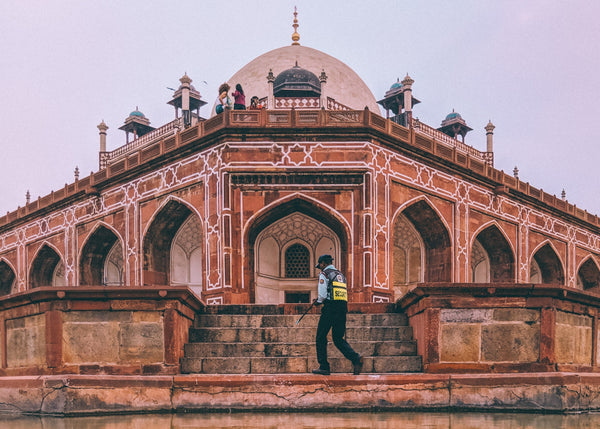 Historic building with intricate architecture reflected in water, person walking on steps